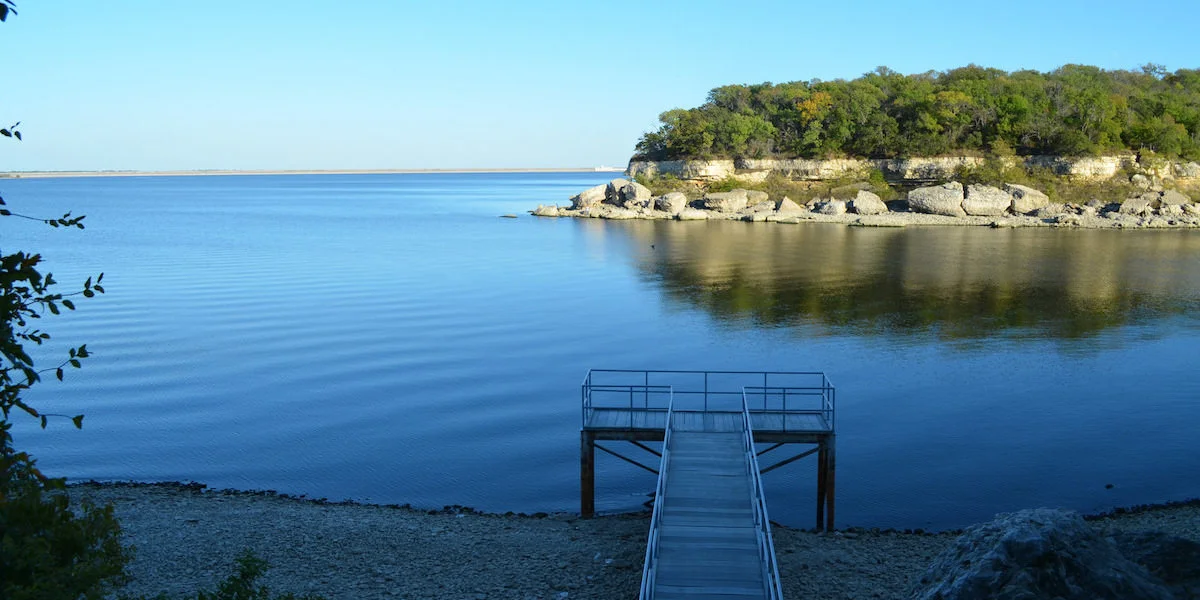 Lake Texoma wooden dock on calm blue waters with rocky shoreline and trees
